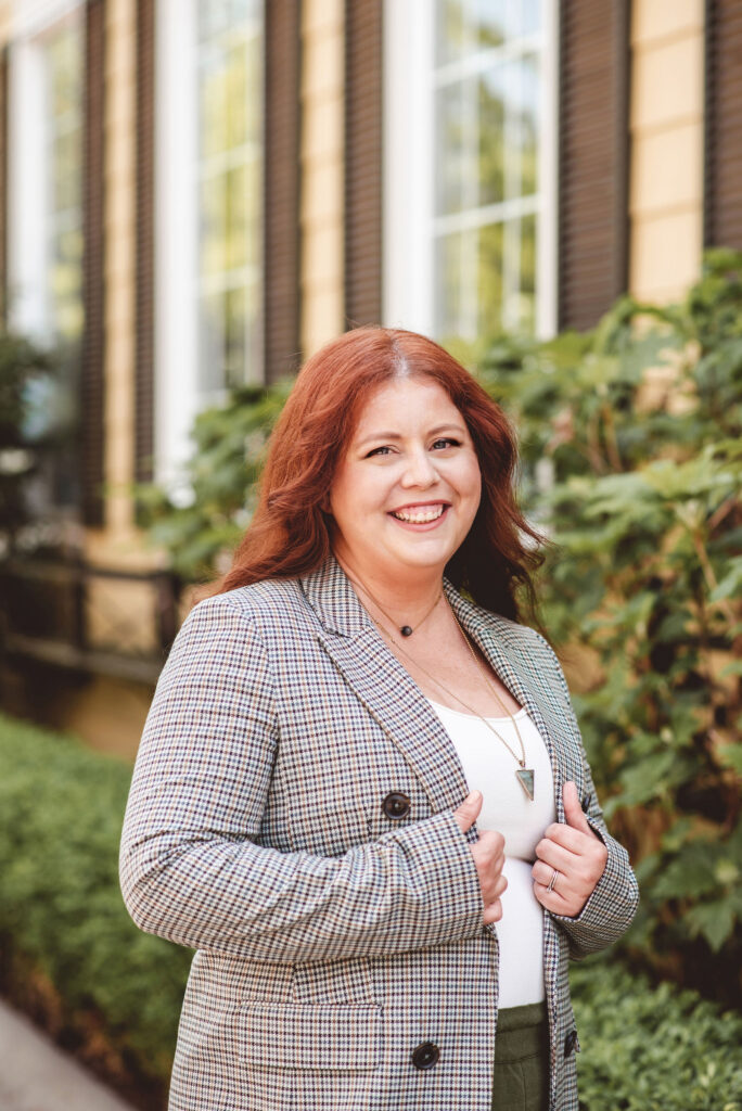 Smiling woman outdoors in plaid blazer, representing confidence and connection to hunger and fullness cues.