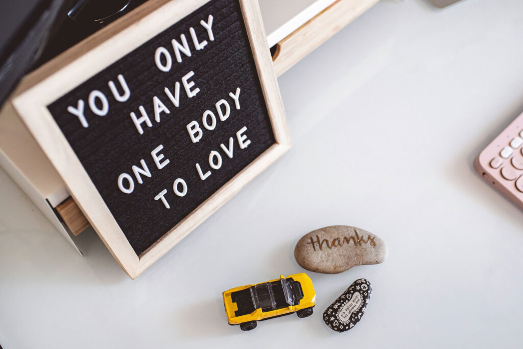 Sign reading 'You only have one body to love' alongside gratitude rock, symbolizing body respect.