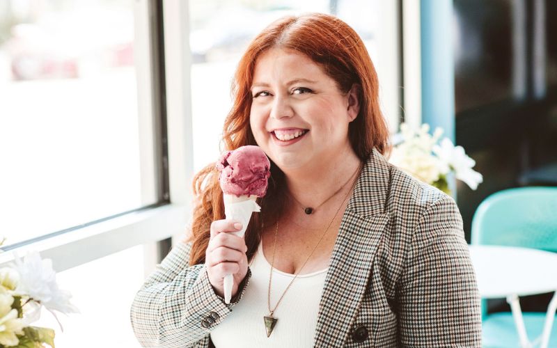 Meredith eating a blueberry ice cream in a cone.