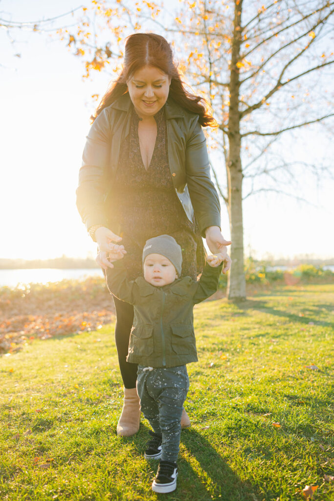 Mother holding toddler’s hands on a sunny walk, finding peace away from holiday diet talk.