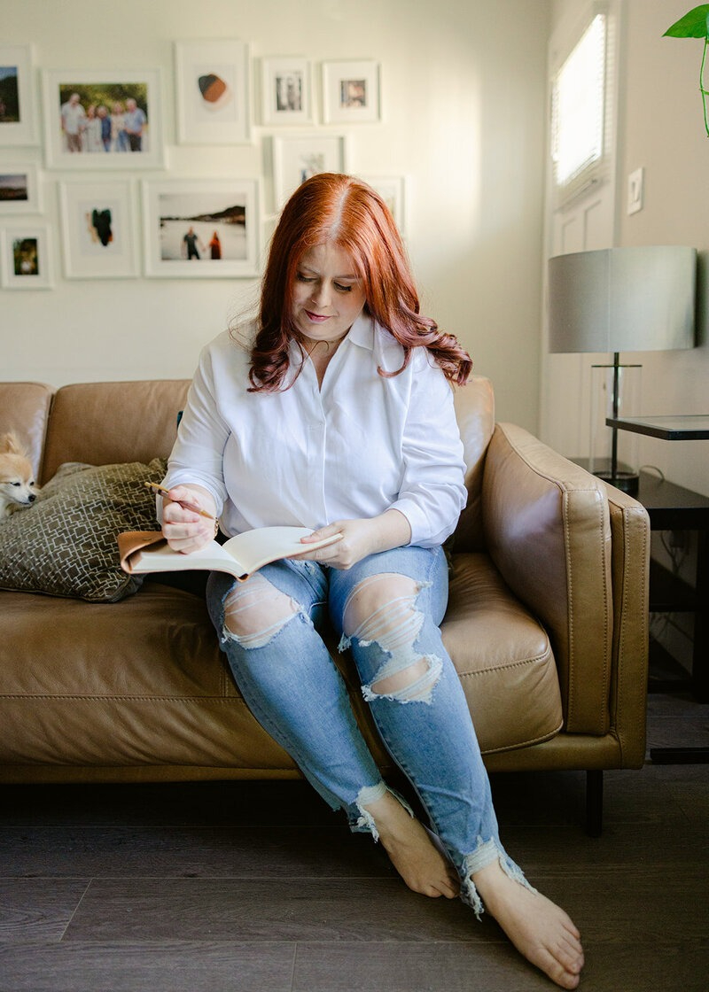 Woman journaling on a couch, representing creating a safe structure with food without falling into restriction.