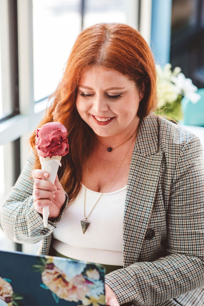 Woman smiling at a berry ice cream cone, embracing food freedom and challenging forbidden foods gently.