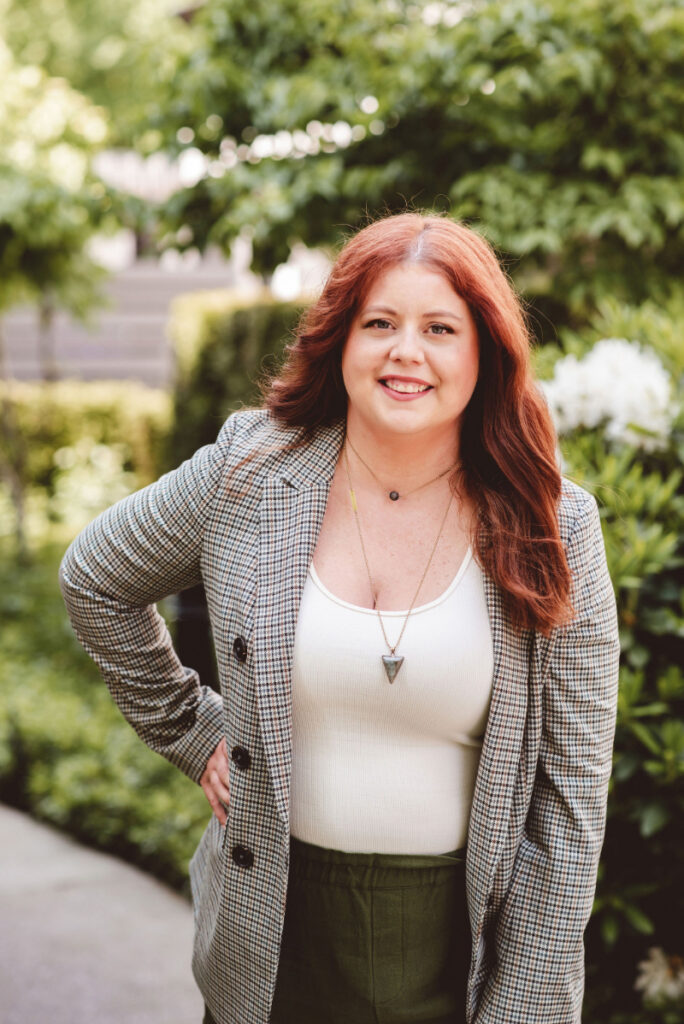 Woman sitting on couch at night scrolling her phone and snacking, illustrating nighttime eating linked to stress and exhaustion.