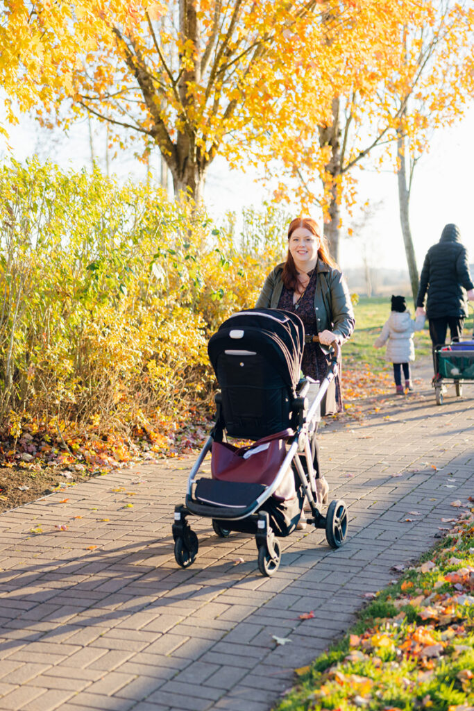 Mother pushing a stroller outdoors, representing body image healing through everyday movement and self-compassion.